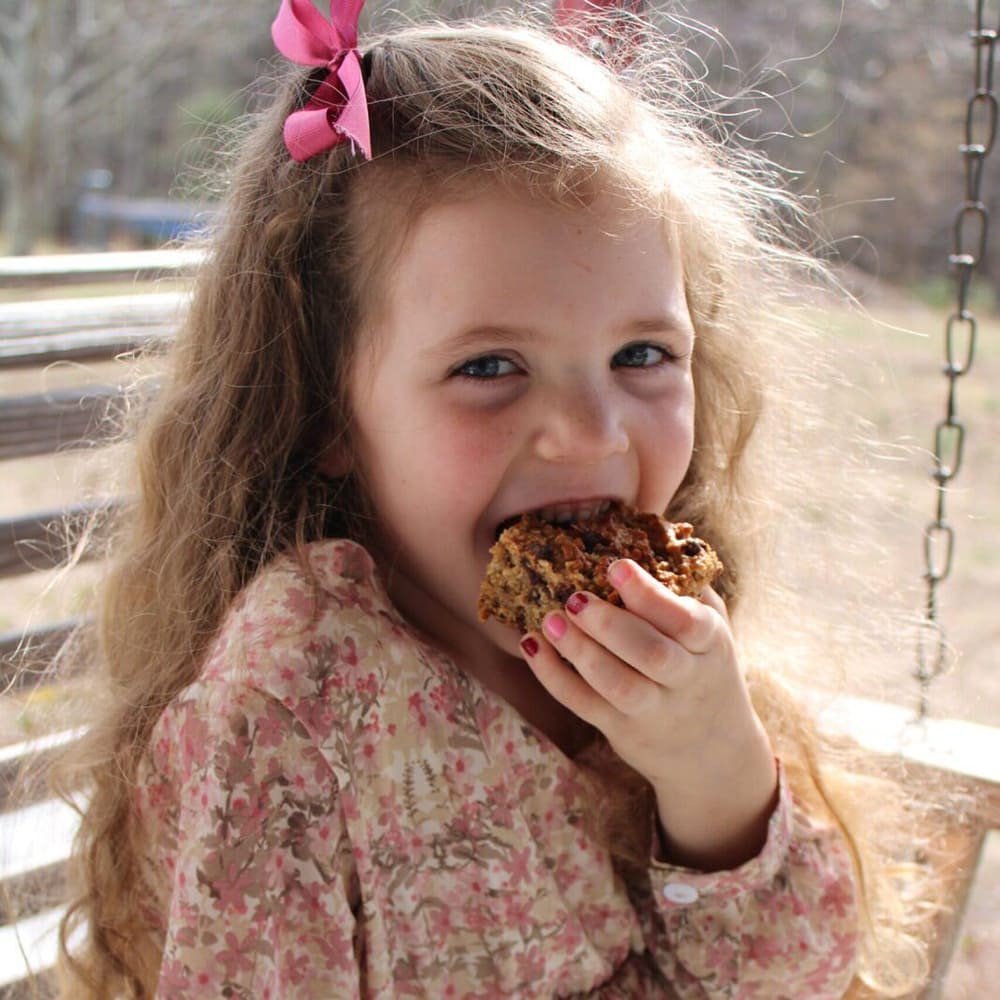girl eating a homemade granola bar on a porch swing