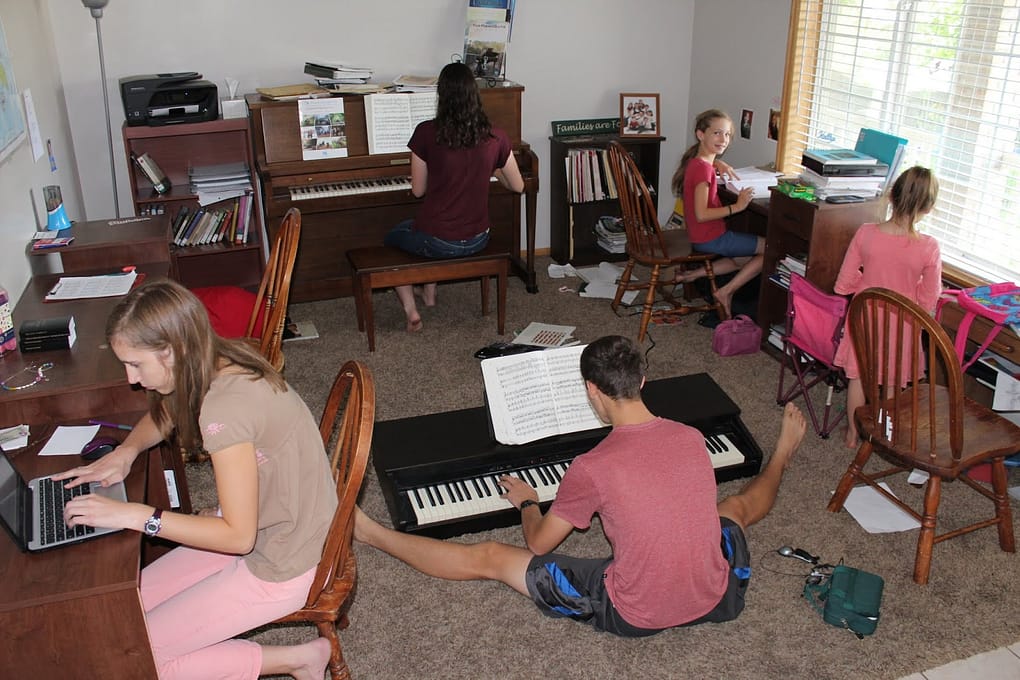 schoolroom kids work on school and play the pianos in a homeschool classroom