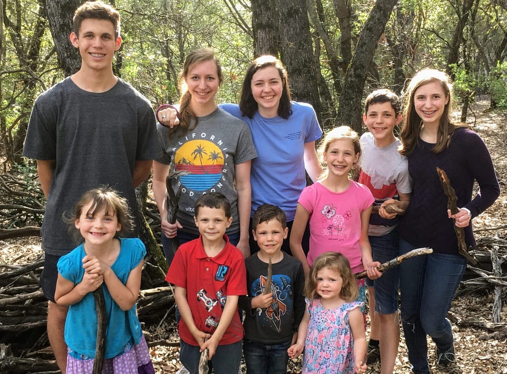 10 siblings playing in the woods with sticks