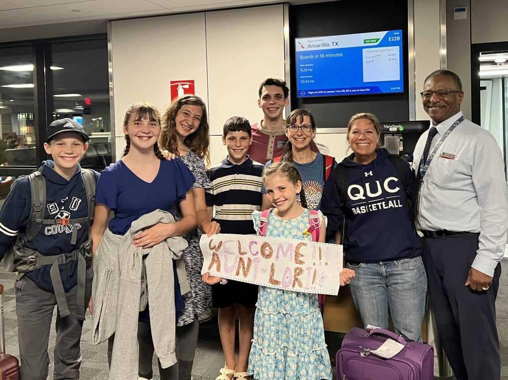 family at airport with welcome sign
