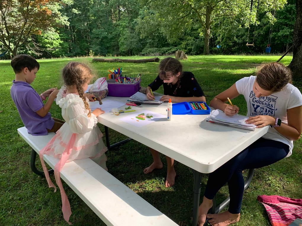 kids do art on the picnic table outside