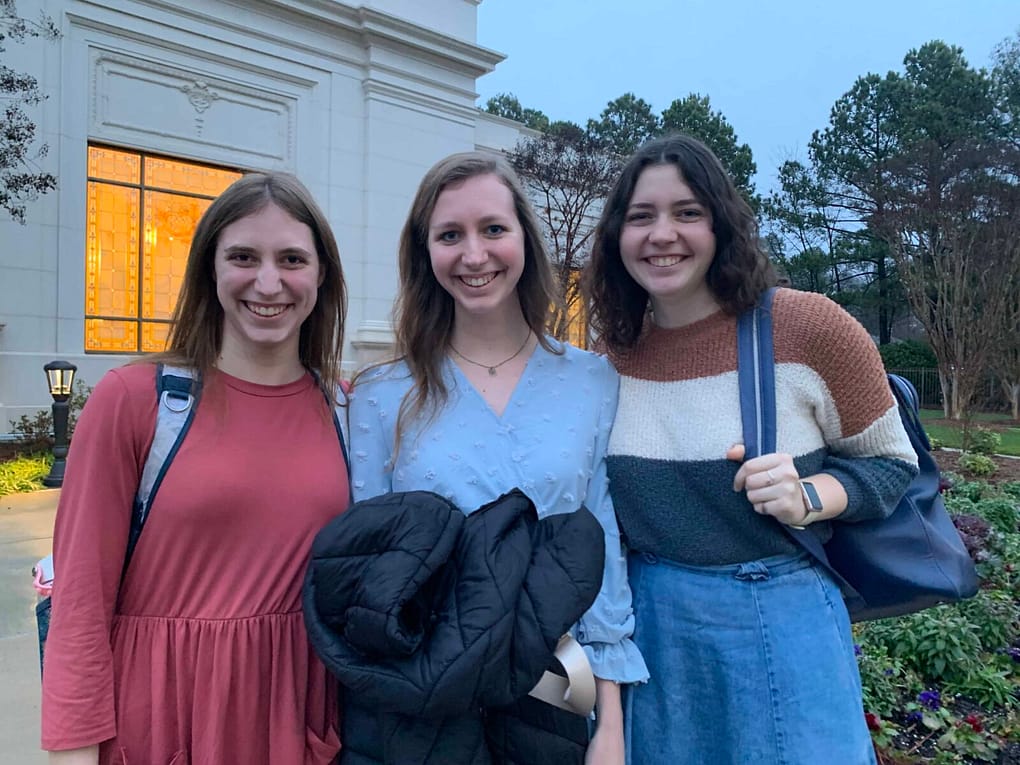 3 sisters dressed up, holding backpacks at the Raleigh Temple, ready to go inside.