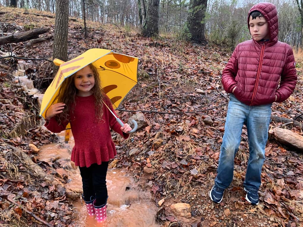 children playing in a muddy stream in the rain in winter