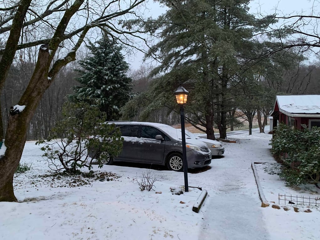 driveway with snow on the van and lightpost and trees