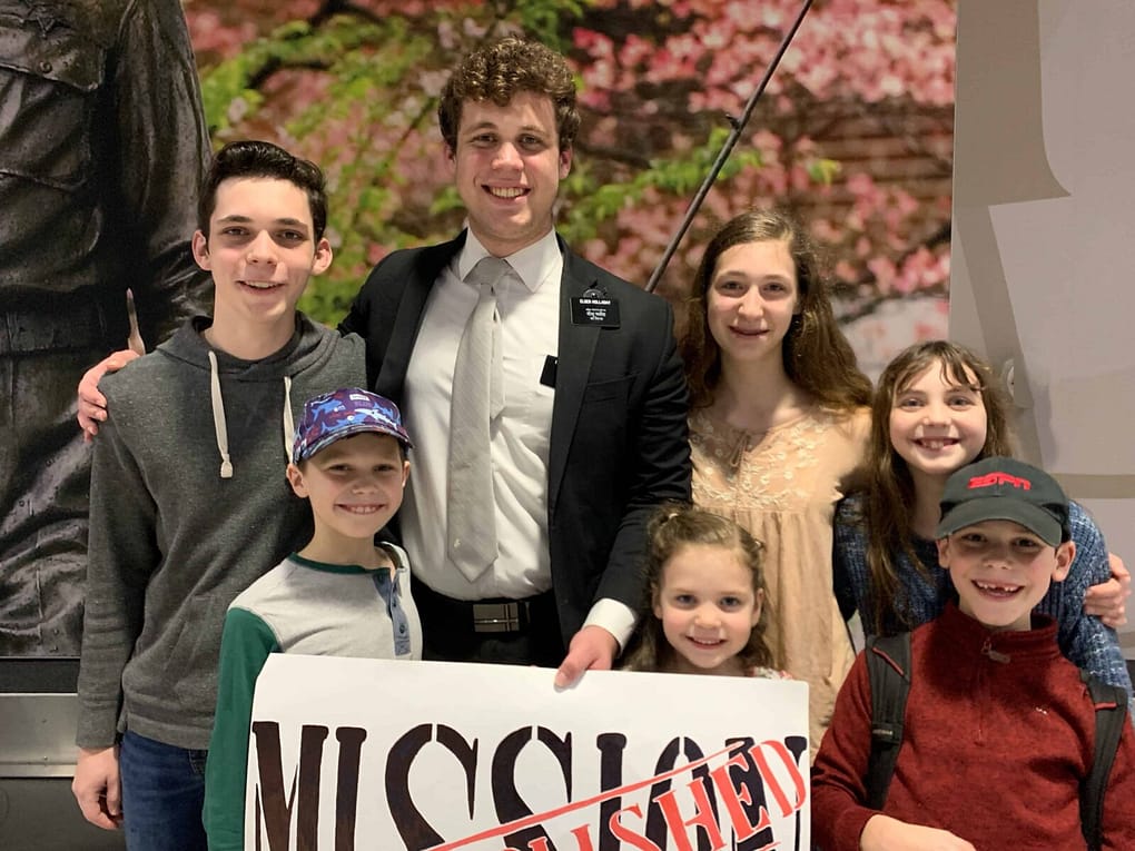 family holding mission accomplished sign at the GSO airport