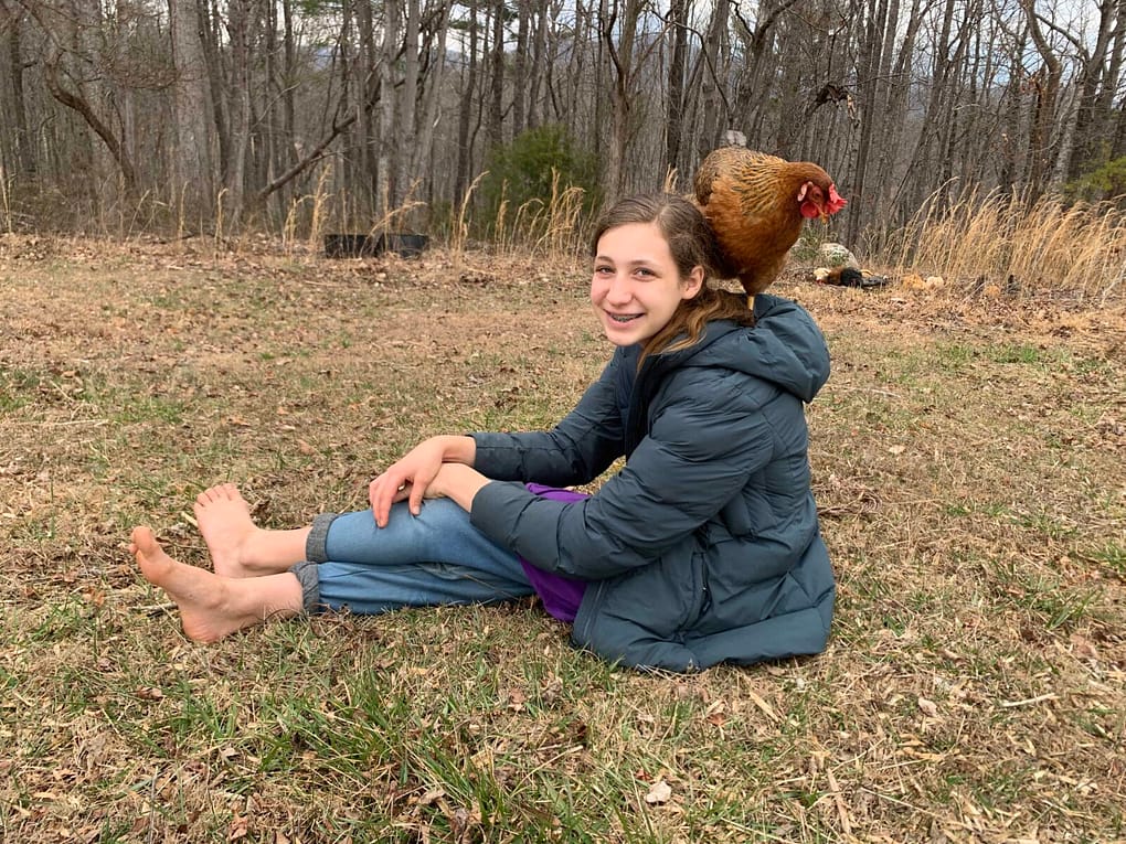 13 year old girl on the grass in winter with a chicken on her shoulder