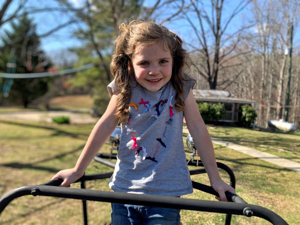 6 year old girl on top of a go cart smiling in early spring