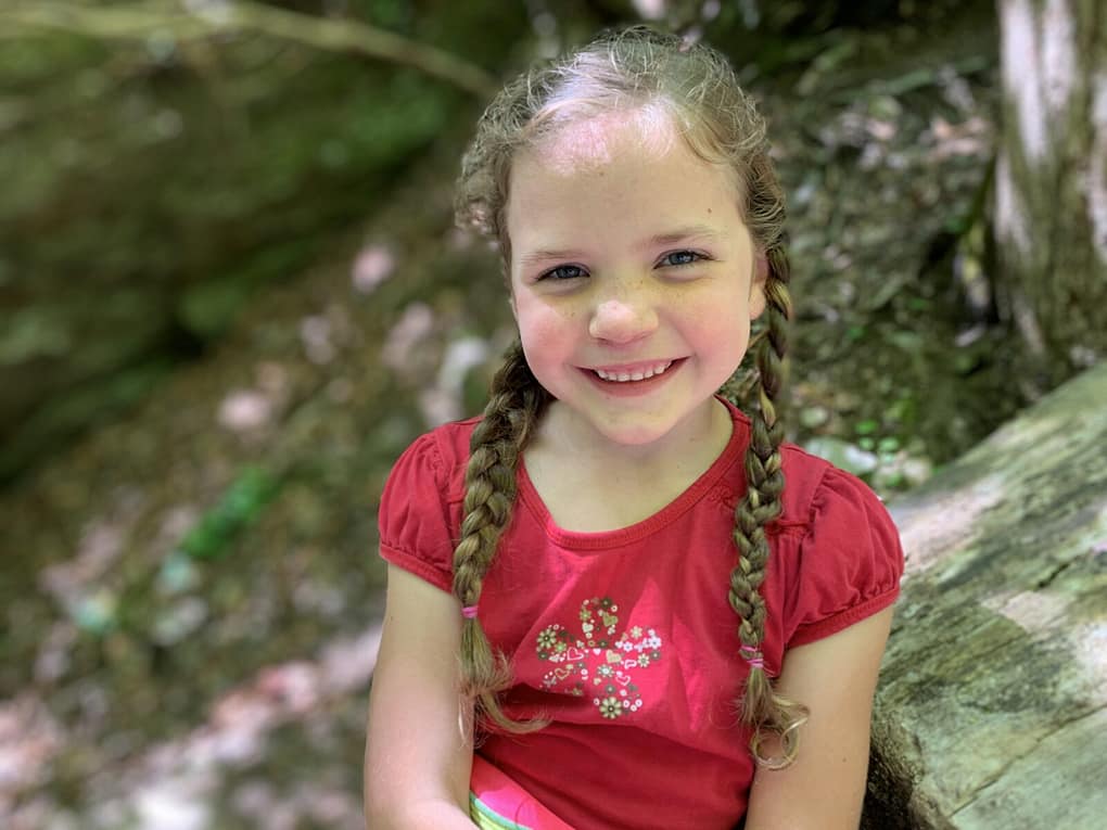 6 year old wearing a red shirt and smiling on a hike