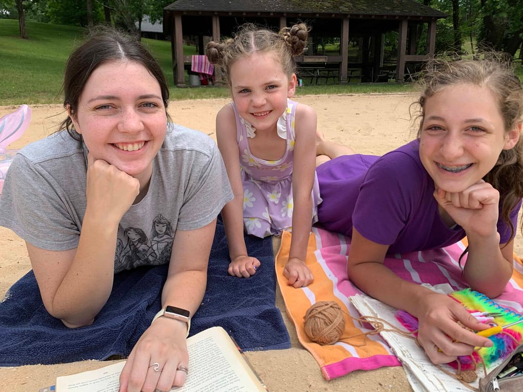 three sisters lying on towels at the beach