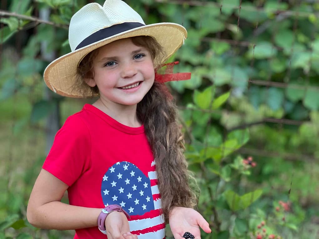 adorable girl in red 4th of July shirt and cowboy hat