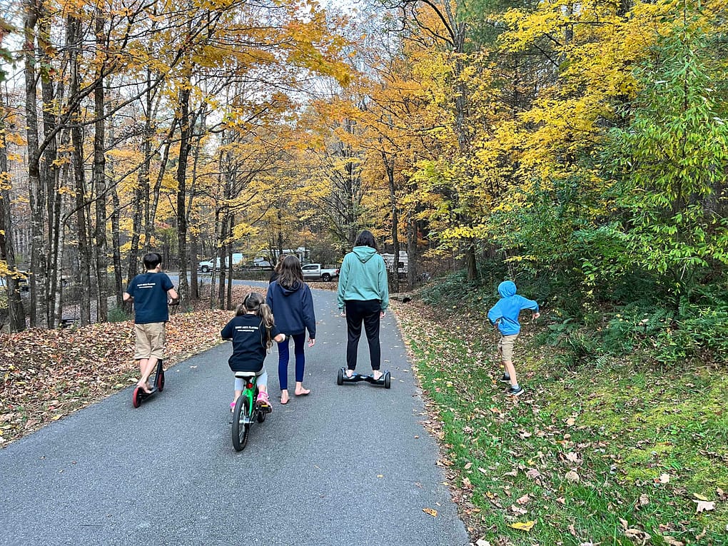 6 kids riding around a campground in fall