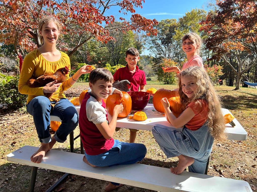 five children carving pumpkins on the picnic table
