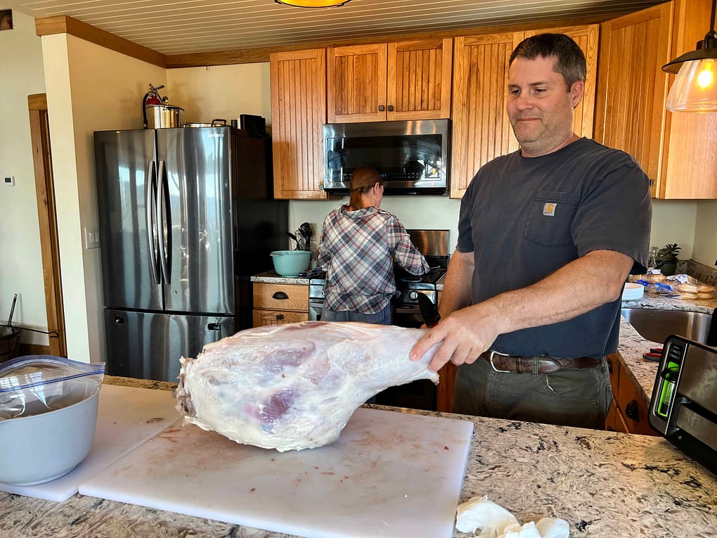 man cutting up deer leg