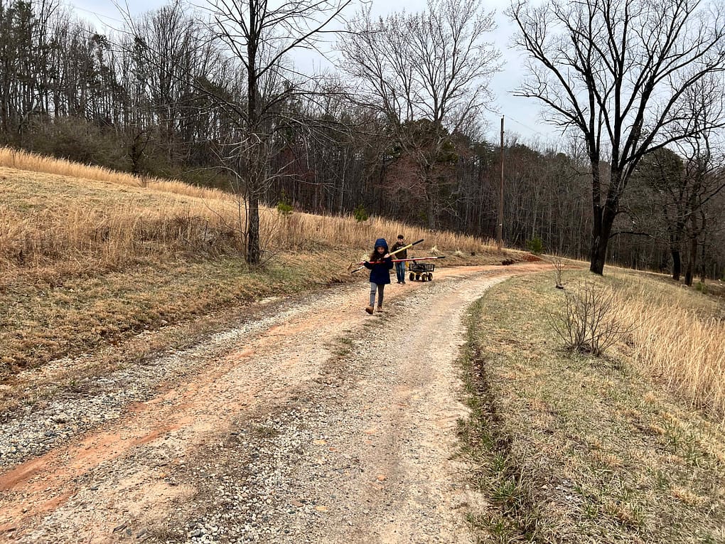kids pulling wagon up a dirt road
