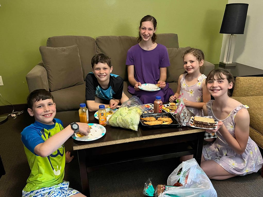 5 kids eating dinner in a hotel with their swimsuits on