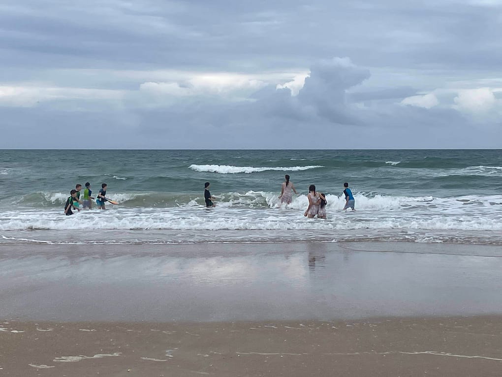 kids swimming in the ocean with clouds overhead