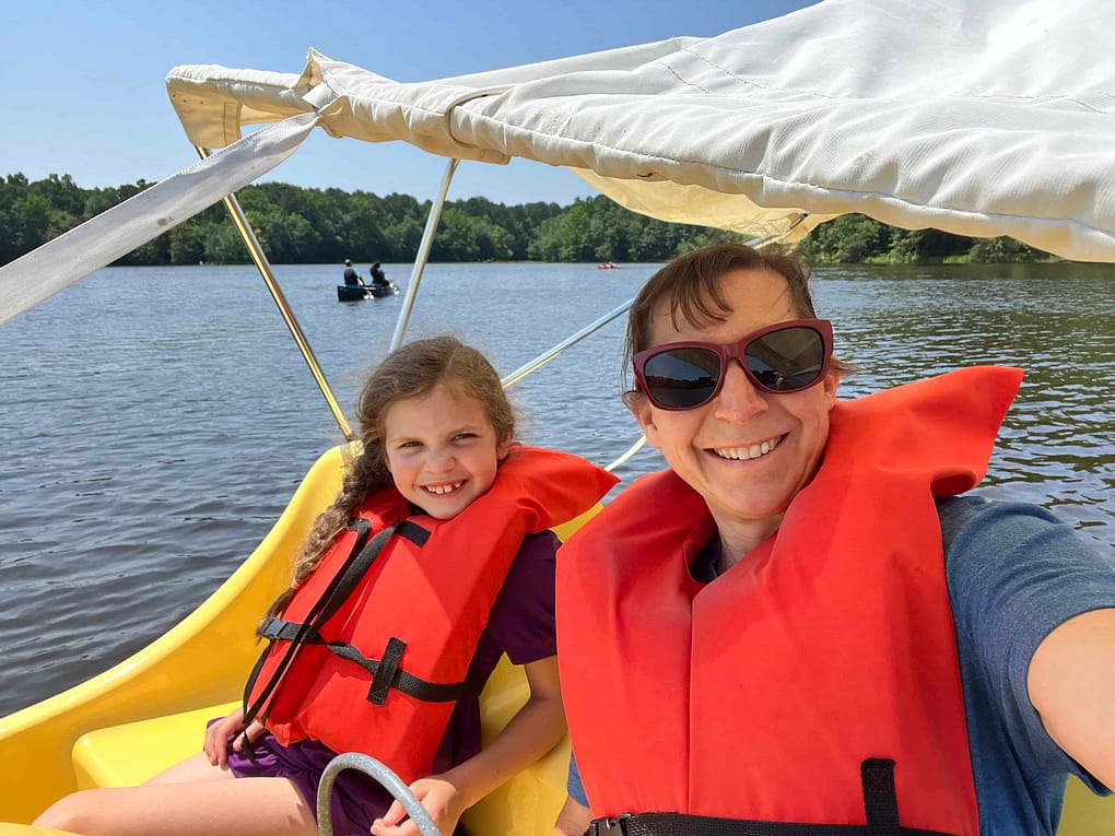 mom and daughter ride a pedal boat together