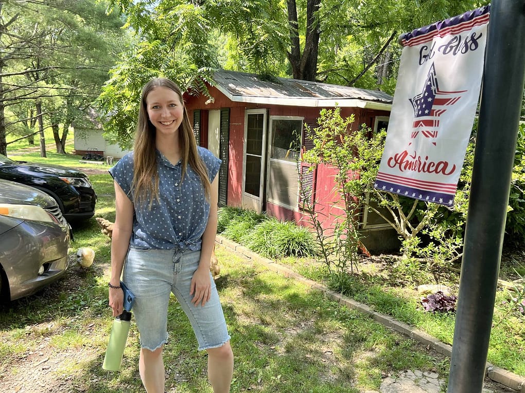 young woman standing next to a festive American flag