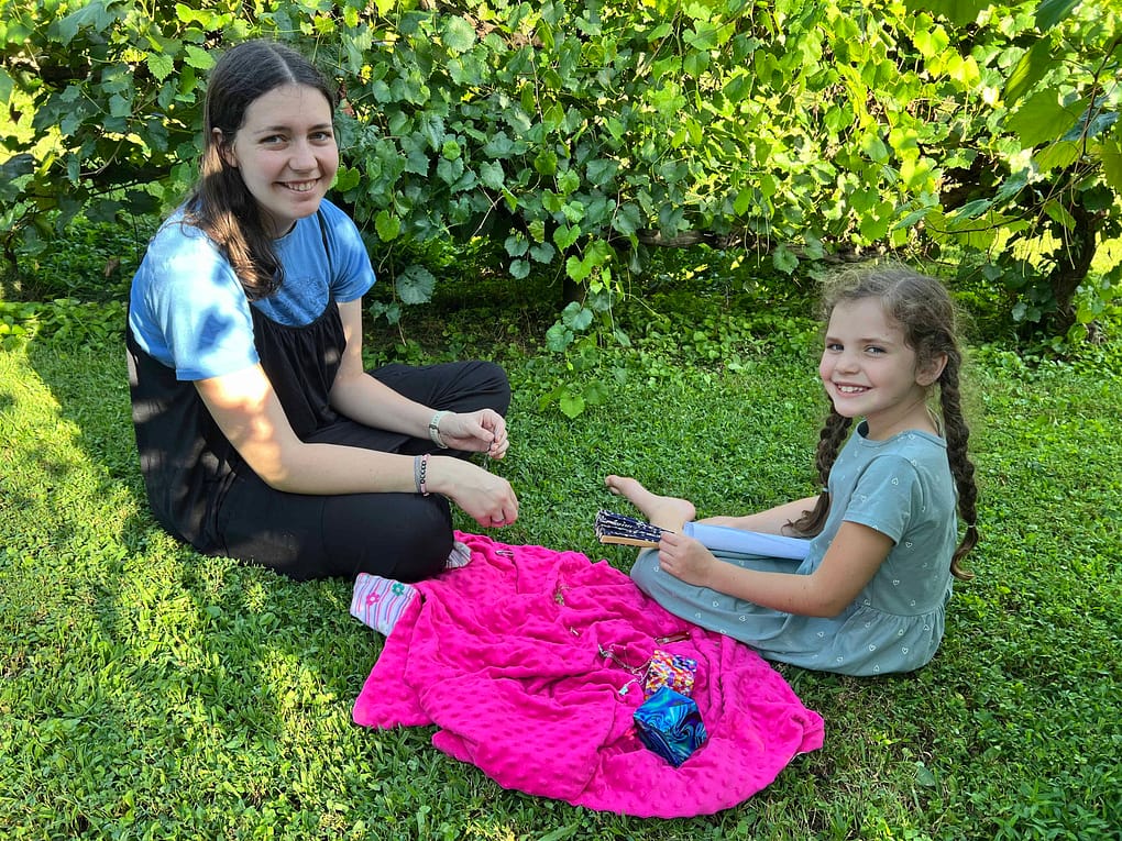22 year old sister and 8 year old sister sitting on the grass