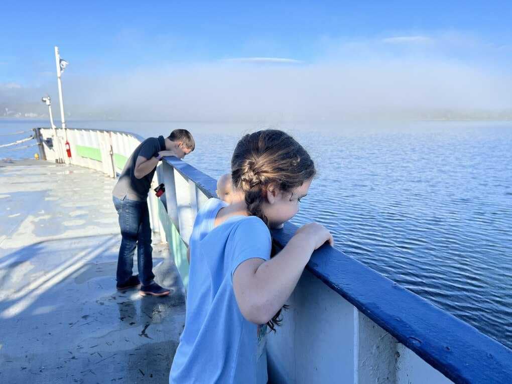 two kids looking over the edge of a ferry