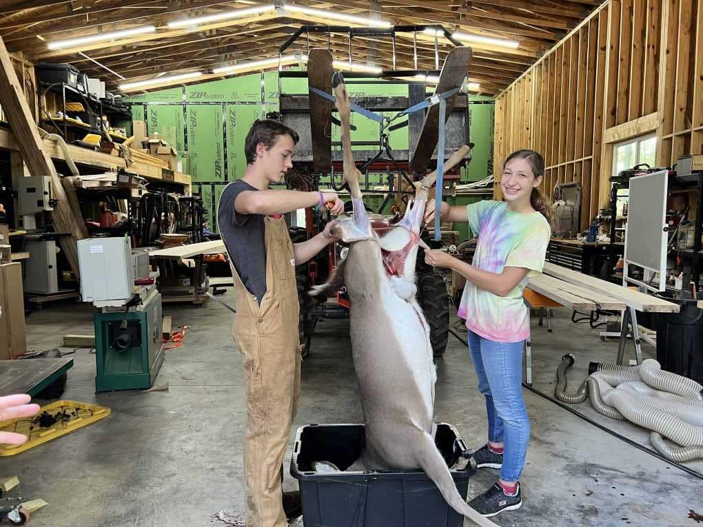 two teens skinning a deer