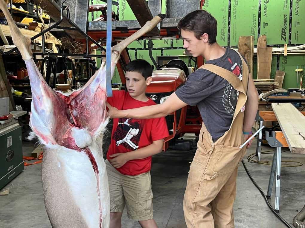 two boys skinning a deer