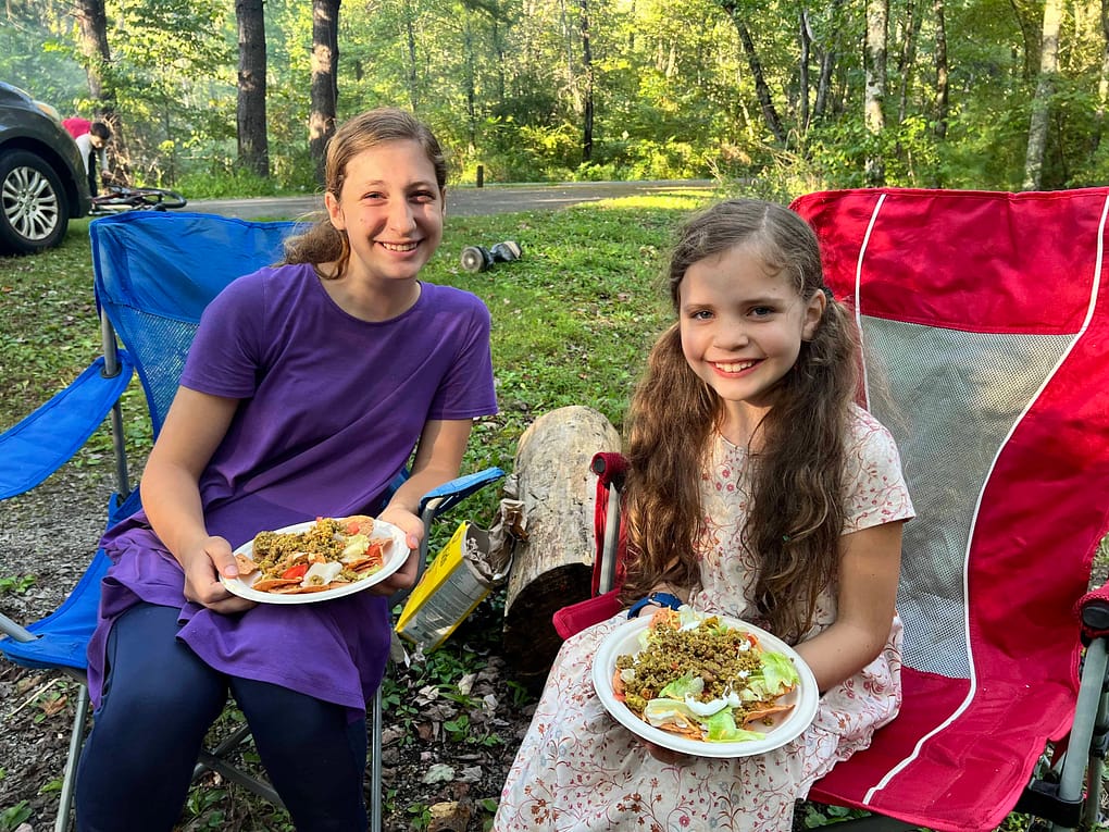 two sisters eating taco salad at a campground