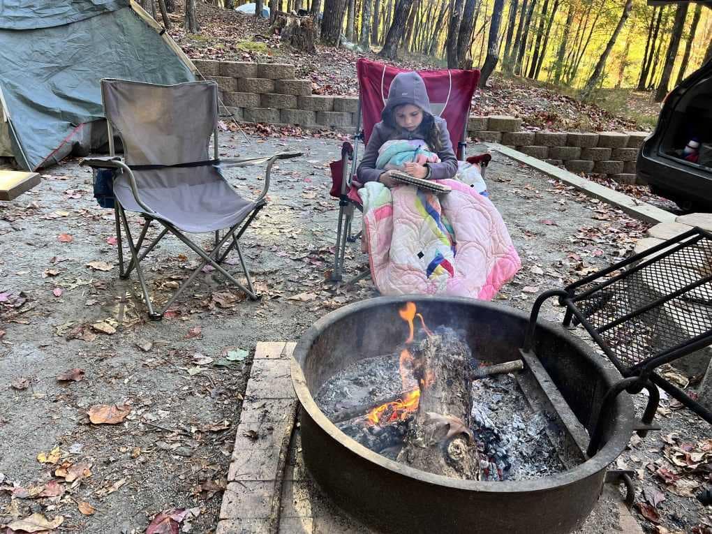 girl reading by campfire