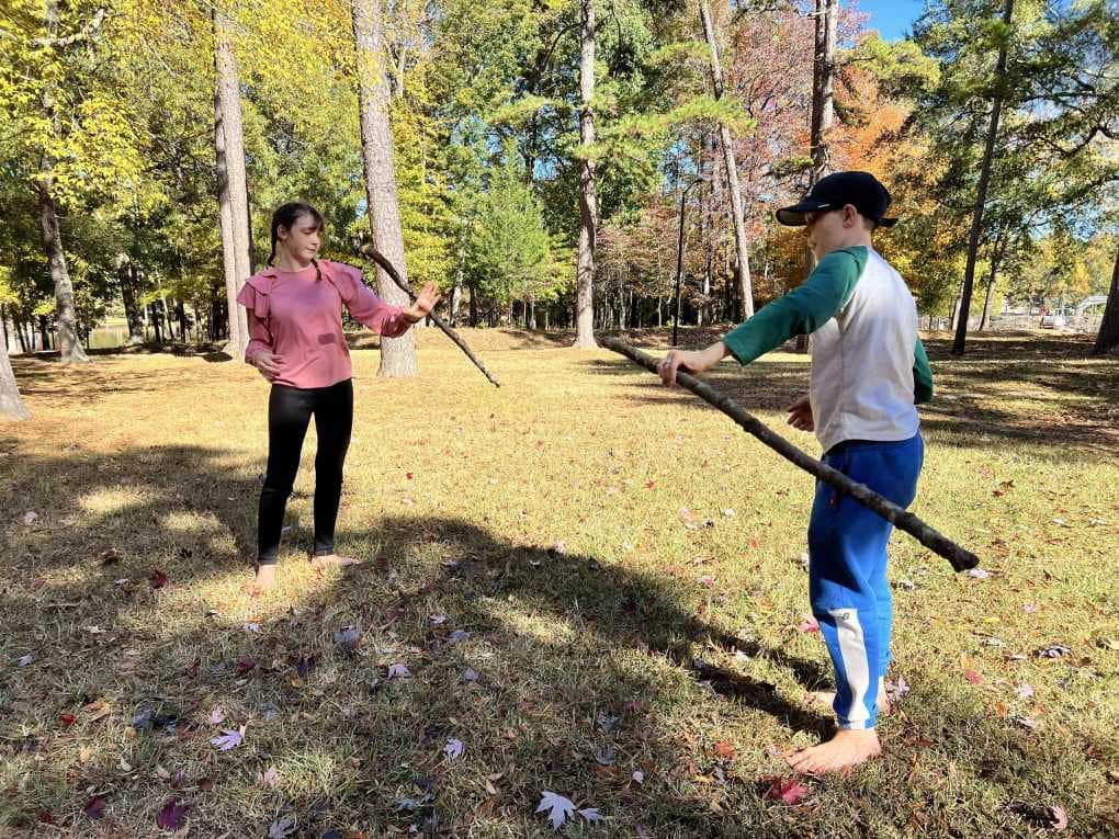 two kids playing with sticks