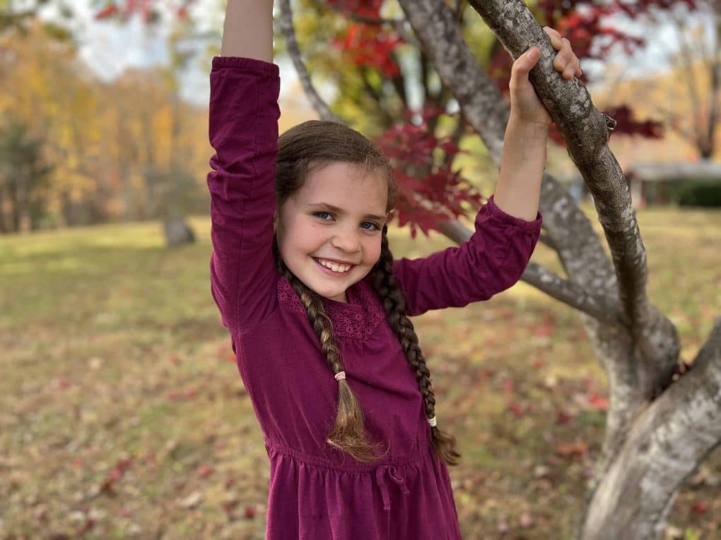 girl hanging from tree in fall