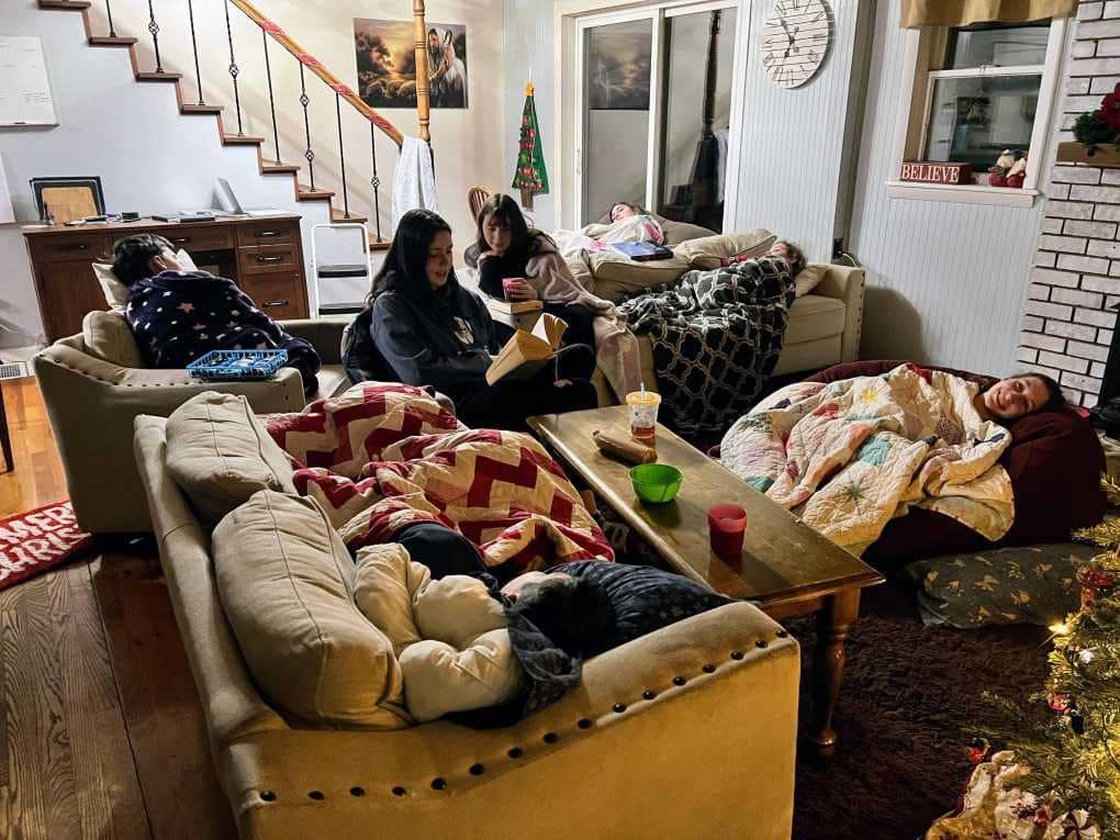 big sister reading to sick kids in the living room