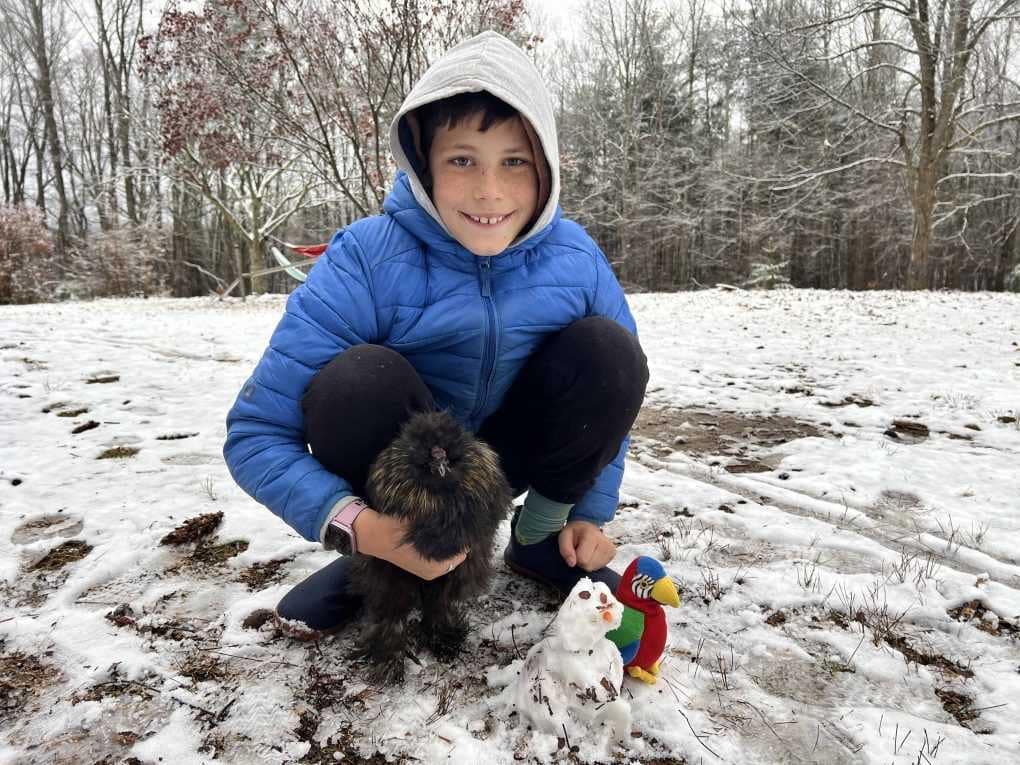 boy in the snow with snowman and chicken