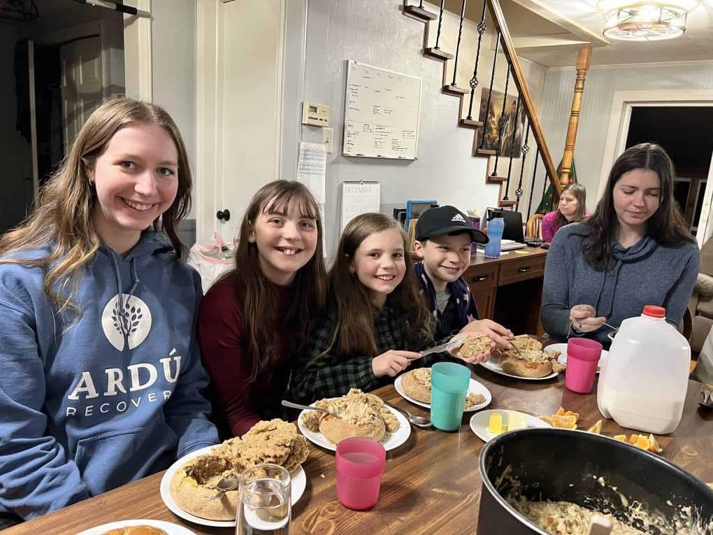 4 kids sitting on a bench at the dinner table