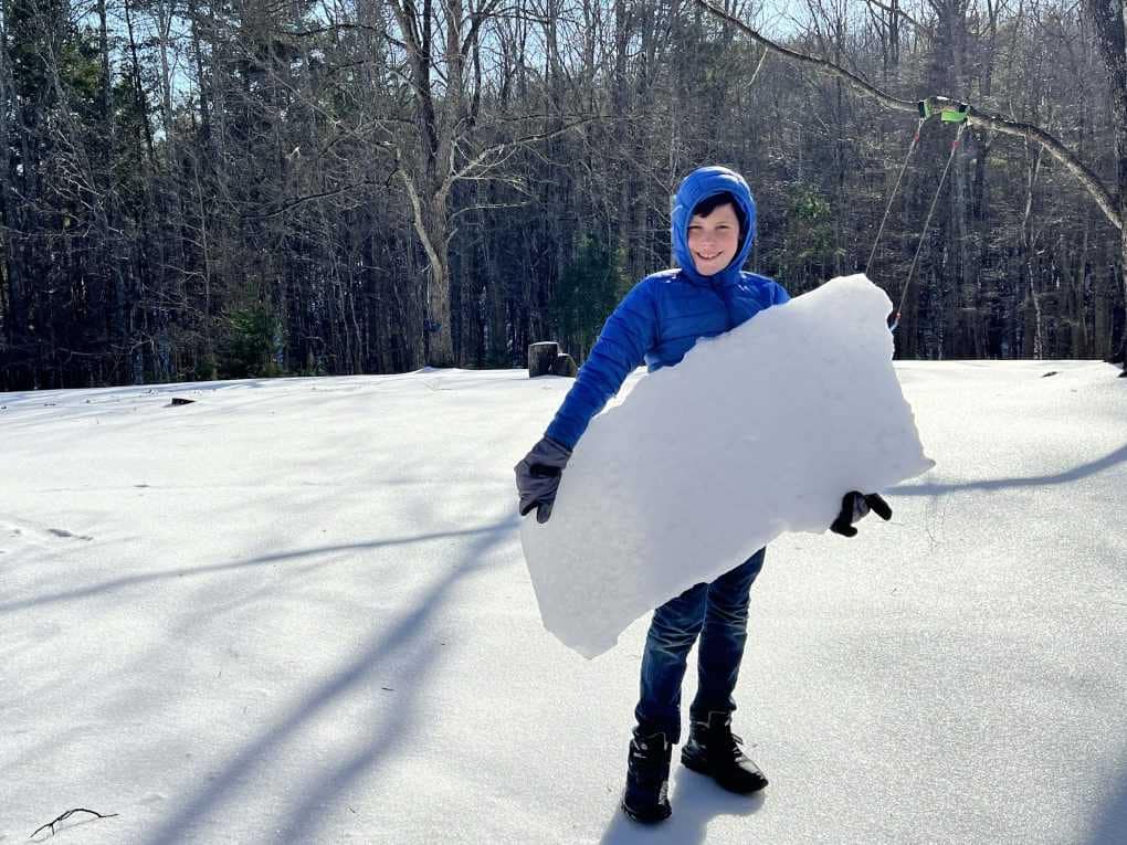 boy holding a huge sheet of ice after an ice storm