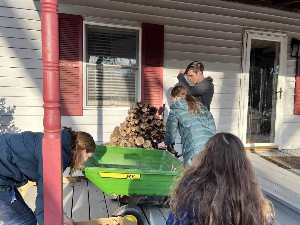 kids stacking firewood on front porch