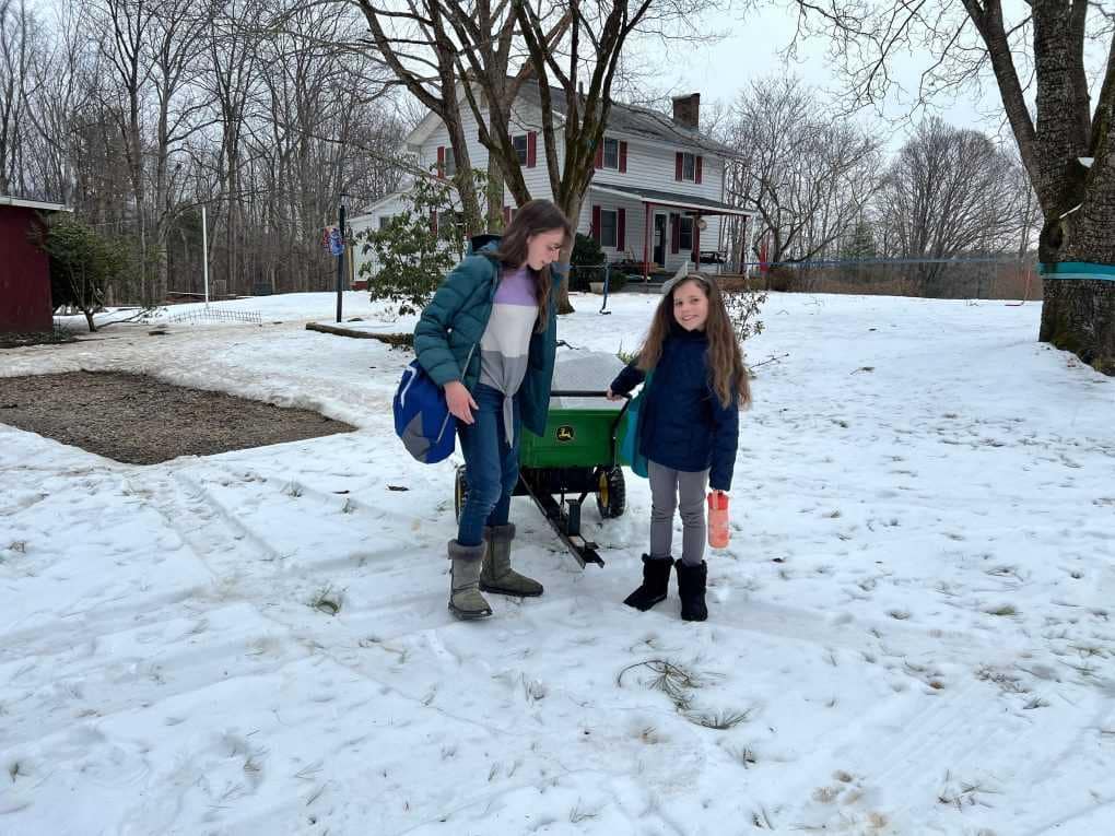 sisters with a cart full of stuff in the snow