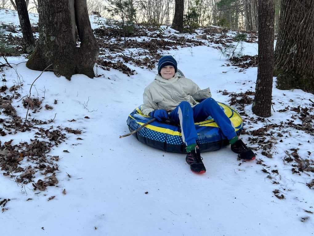 boy tubing down icy woods