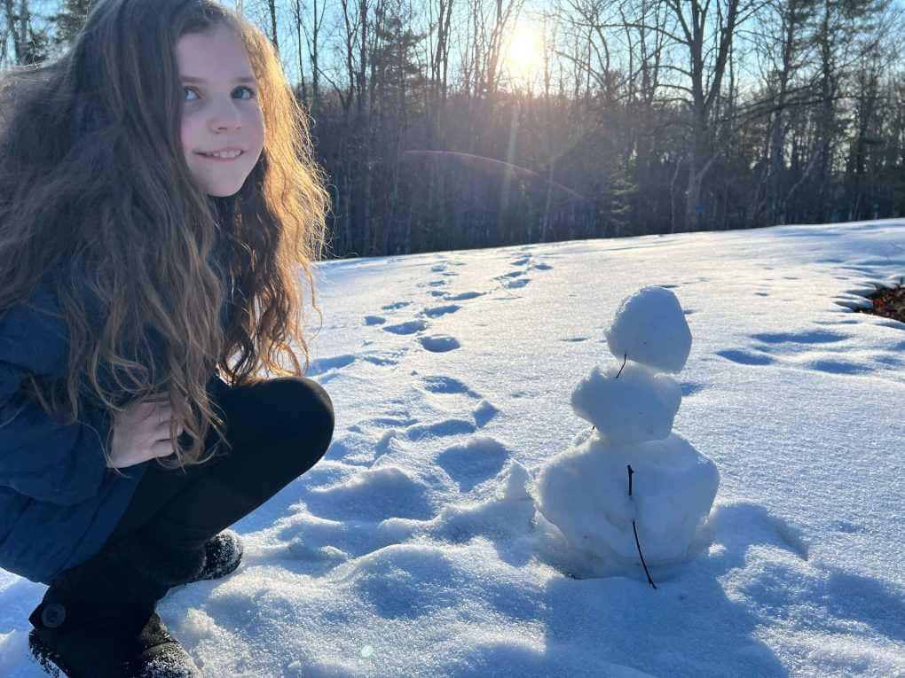 girl with snowman and sunset
