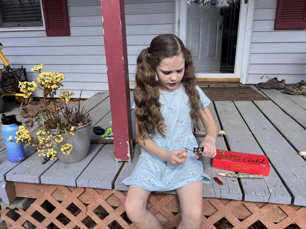girl carving stick with pocketknife