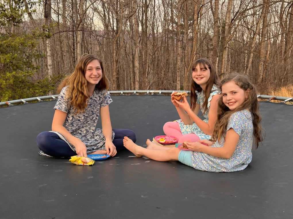 3 sisters eating lunch on the trampoline