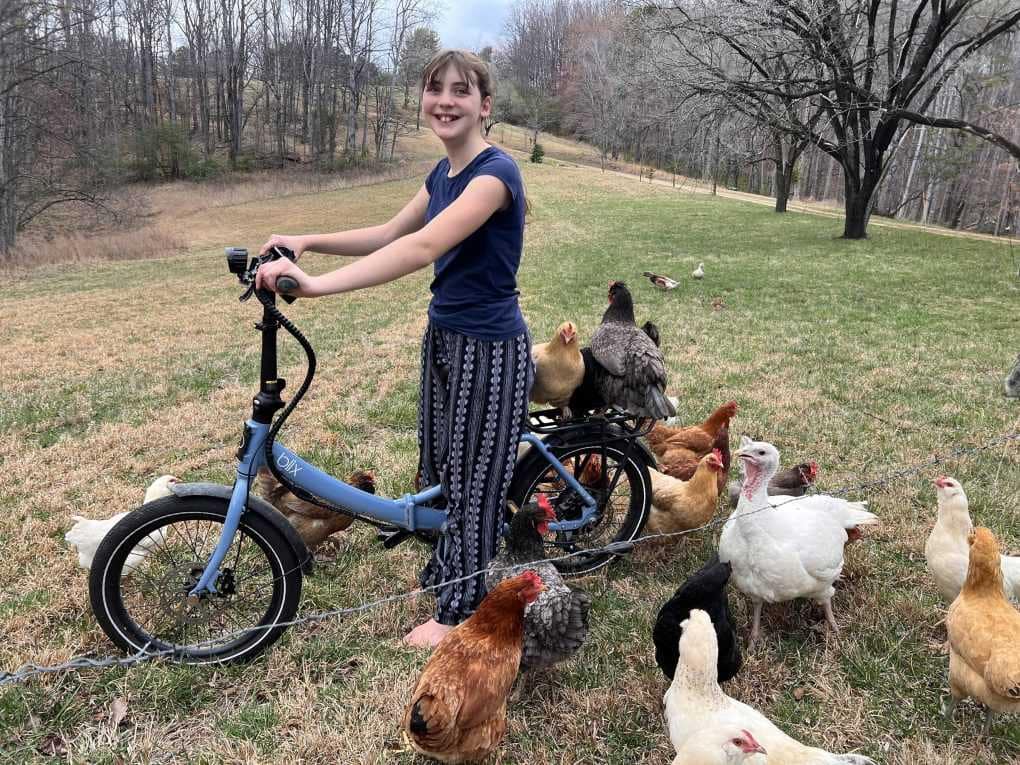 girl riding e-bike with chickens on the back