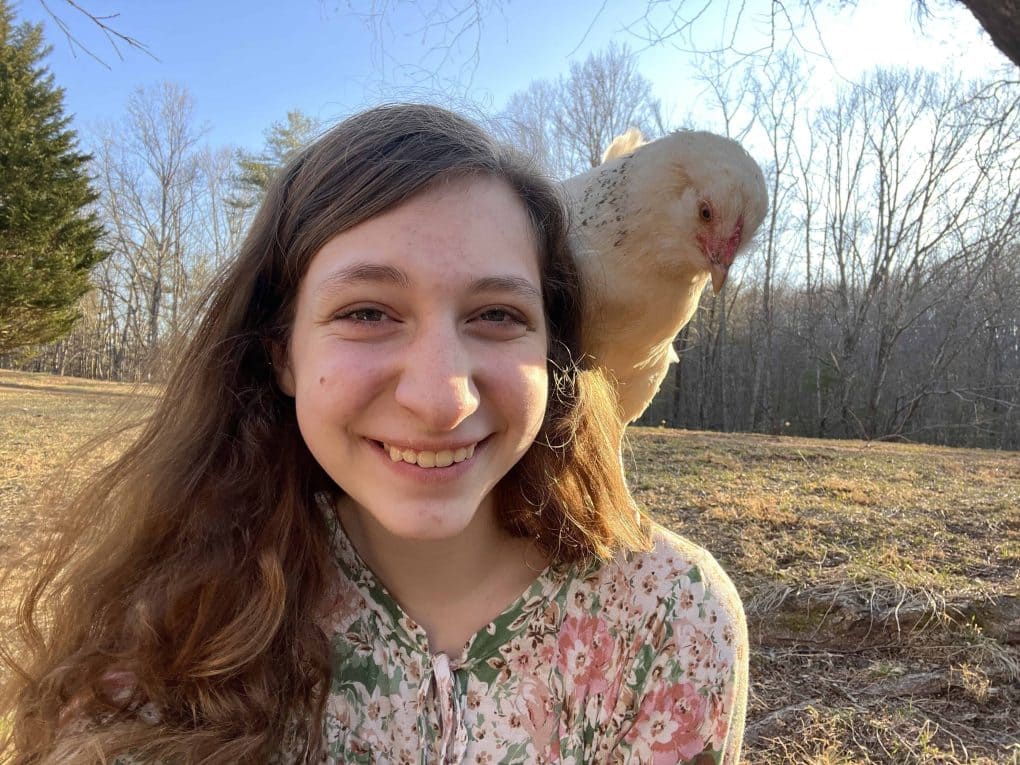 teen girl with small rooster on shoulder