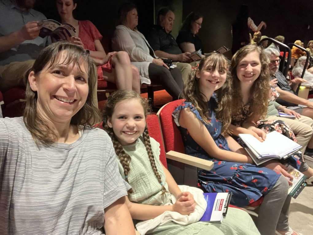 mom and daughters watching a play