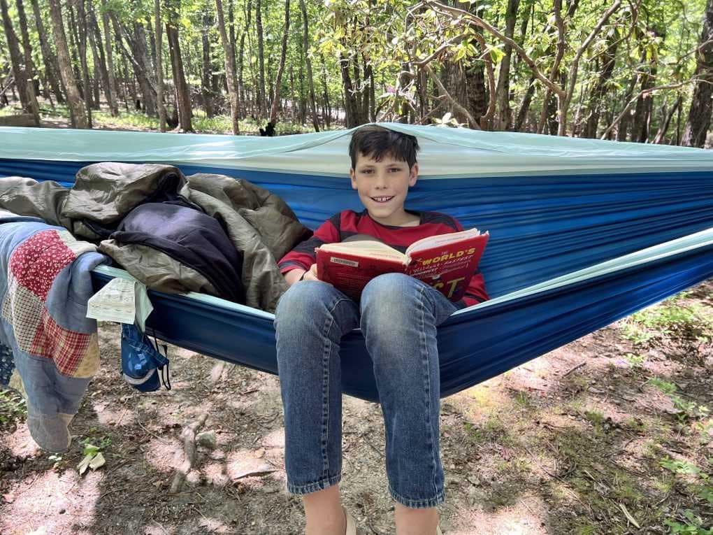 boy sitting in hammock reading