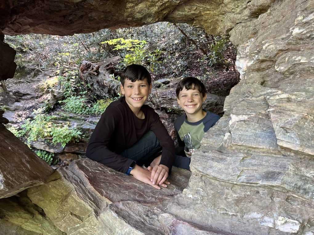 two boys in a rock window hole