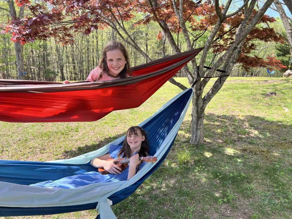 Two girls in bunk bed hammocks with a ukulele