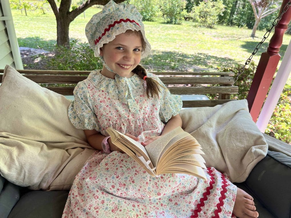 8 year old girl in pioneer clothes on porch swing