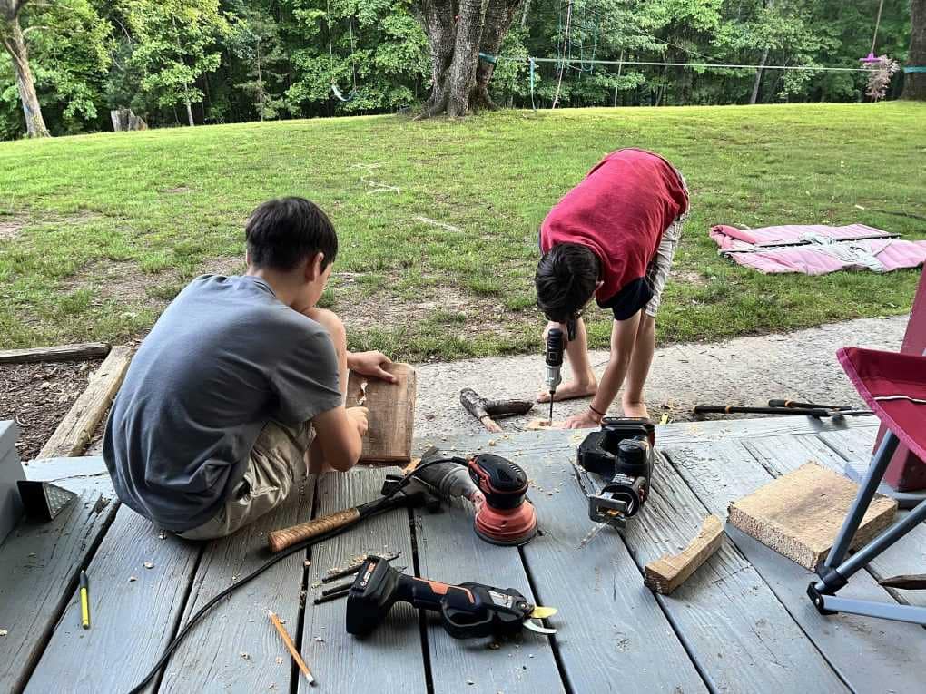 boys wood carving on front porch