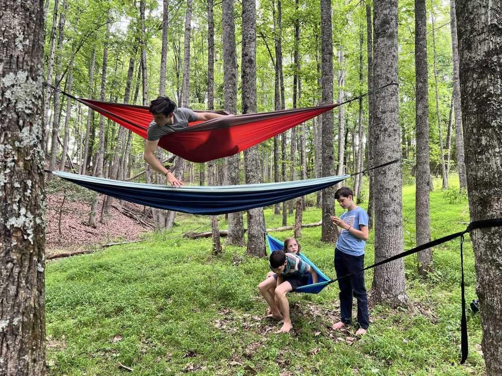 kids playing in hammocks in the woods
