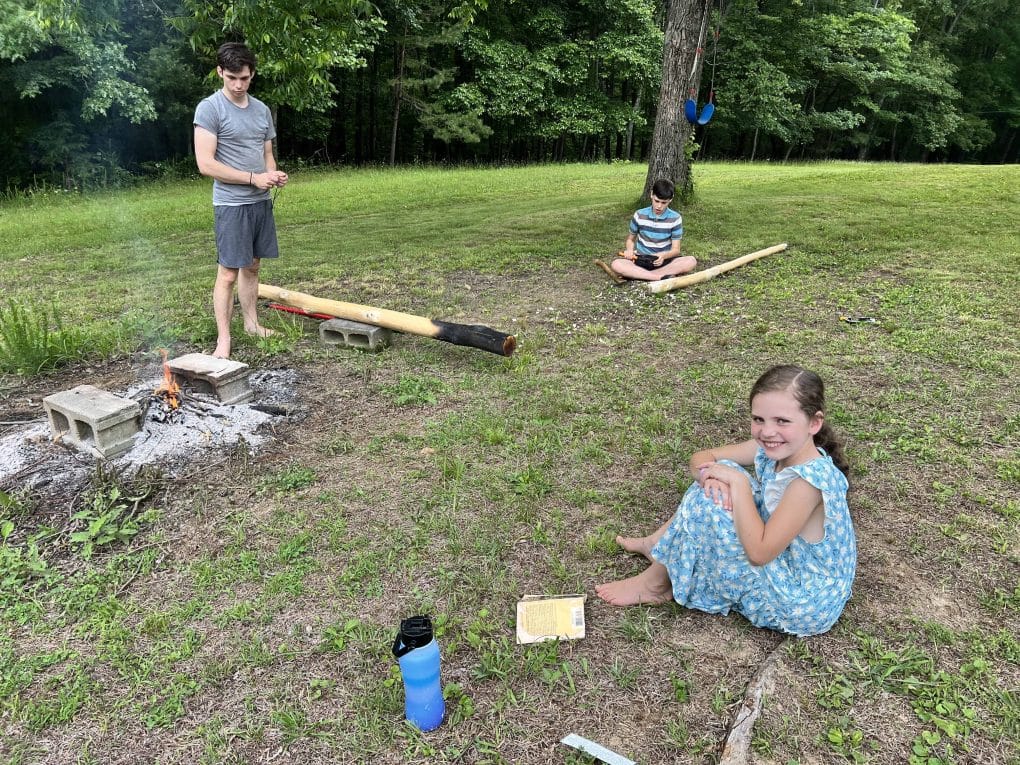 3 kids do wood carving in the yard